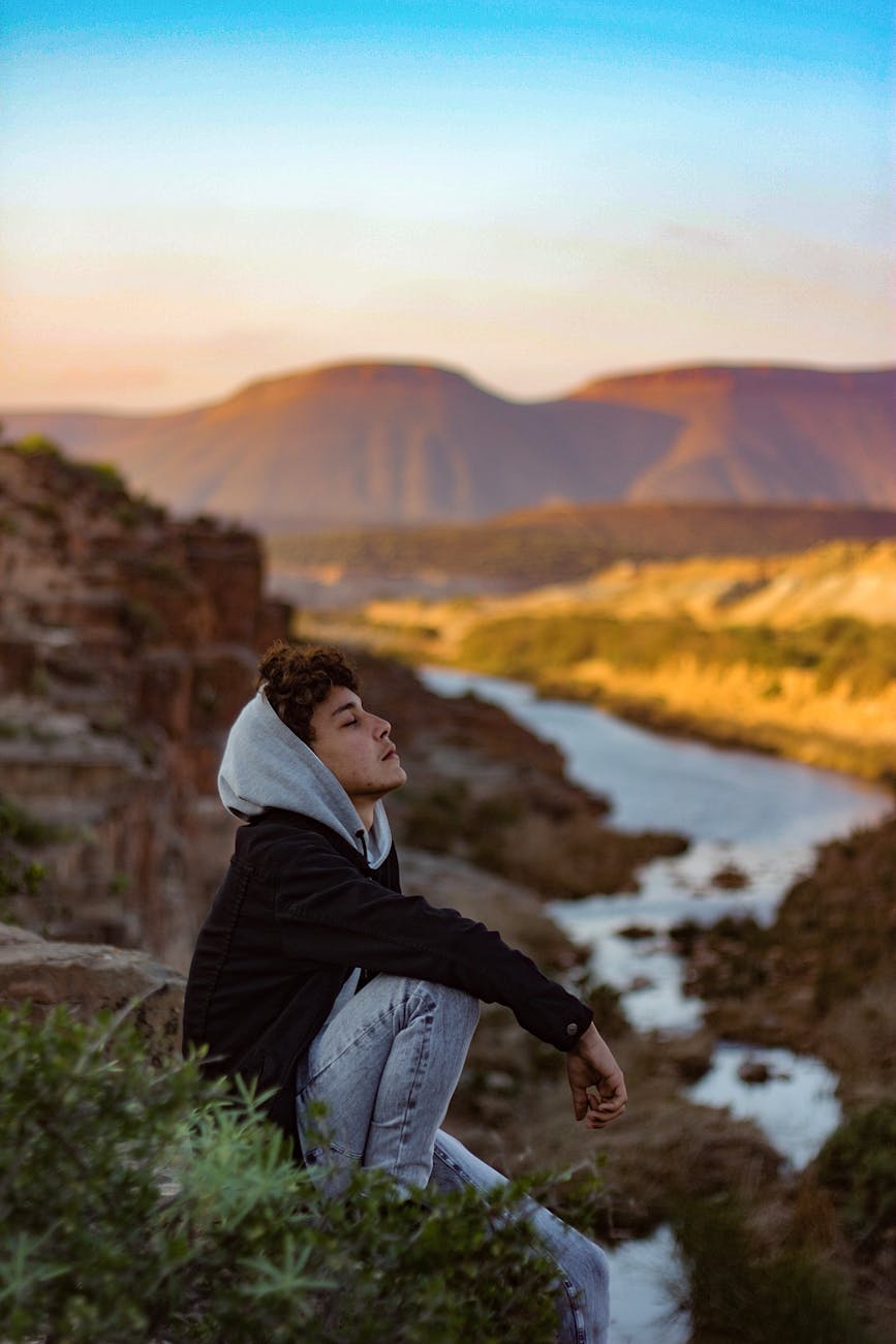 Person in a serene warrior two yoga pose overlooking a city at dusk.